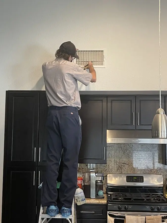 Technician inspecting an air vent during HVAC service in Hudson Falls